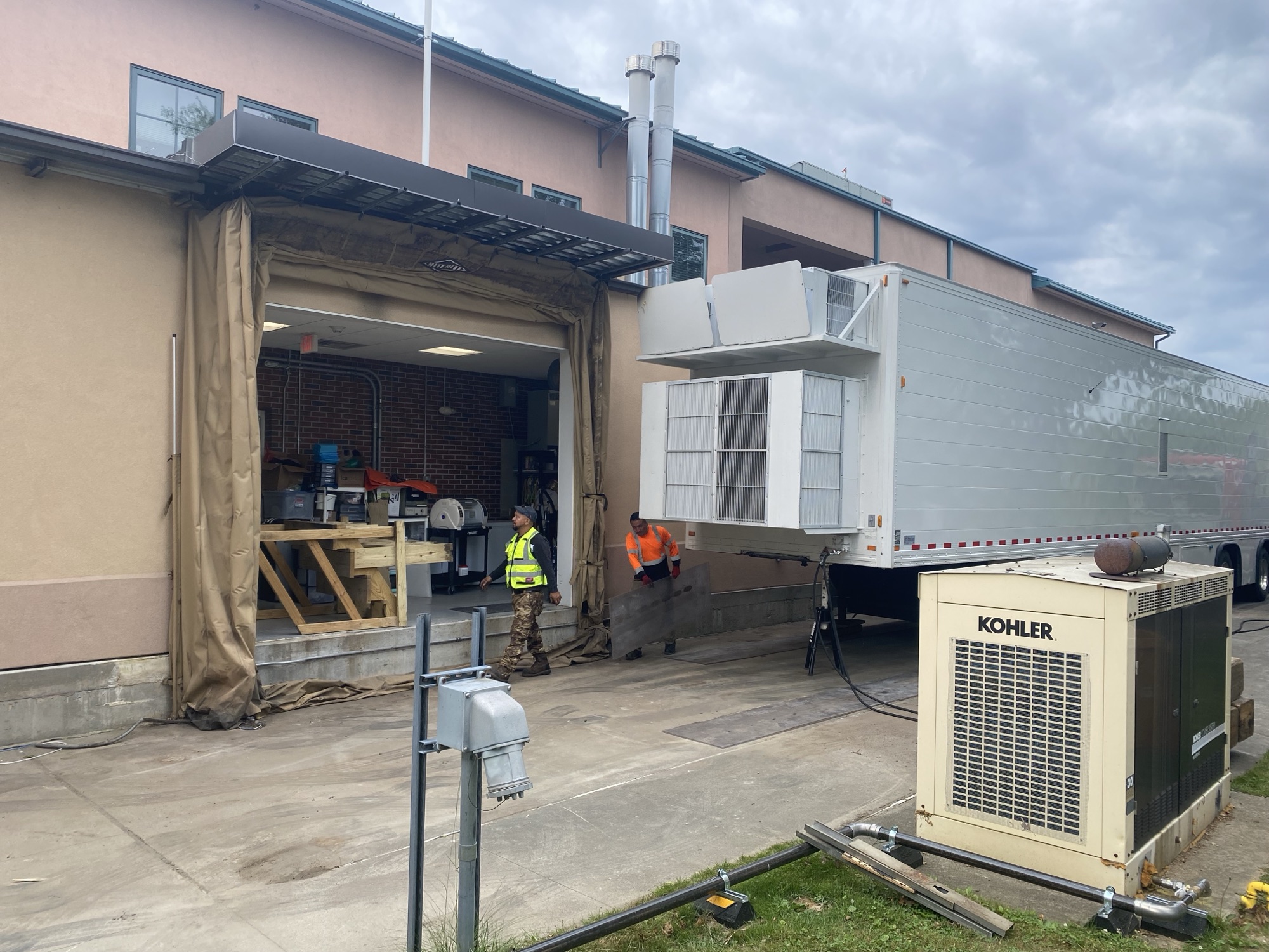 Technicians servicing a mobile imaging coach at the shop with a generator and chiller unit